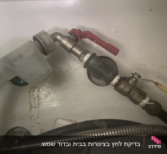 צינור עם ברז אדום וחיבורים מתכתיים